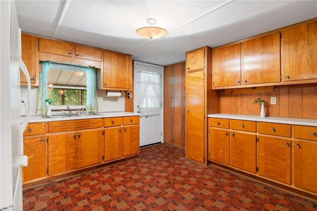 kitchen featuring light countertops, brown cabinetry, and a sink