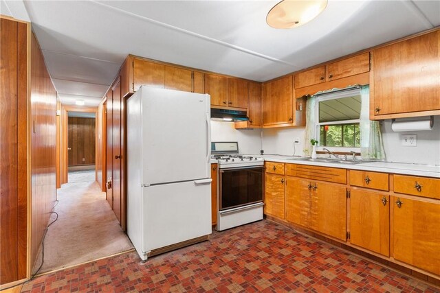 kitchen featuring a sink, white appliances, brown cabinetry, light countertops, and under cabinet range hood