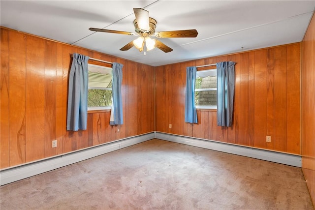 carpeted empty room with a ceiling fan and wood walls
