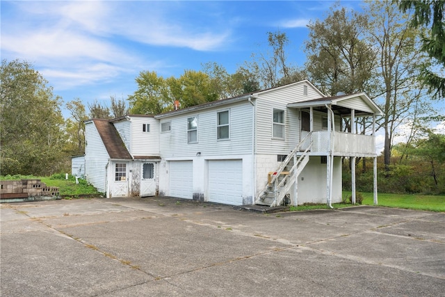 exterior space with stairway, covered porch, a garage, and concrete driveway