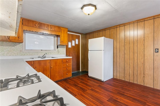 kitchen with brown cabinets, light countertops, a sink, dark wood-type flooring, and freestanding refrigerator