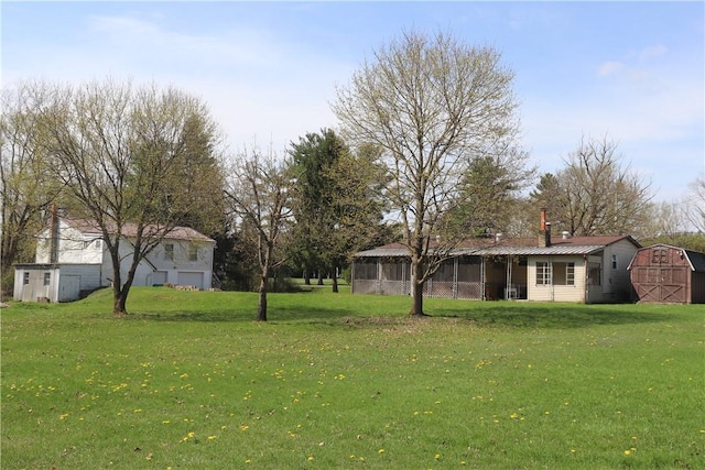 view of yard featuring a garage, a storage unit, and an outbuilding
