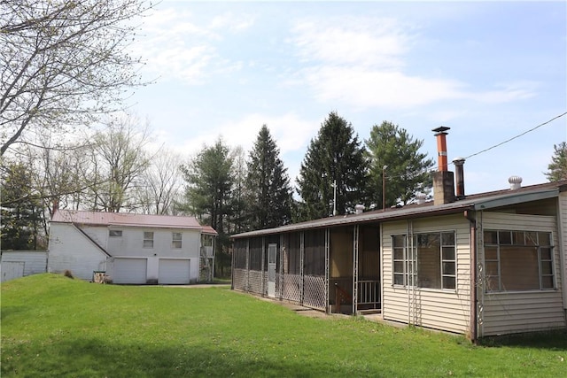 back of house featuring a sunroom, a chimney, and a lawn