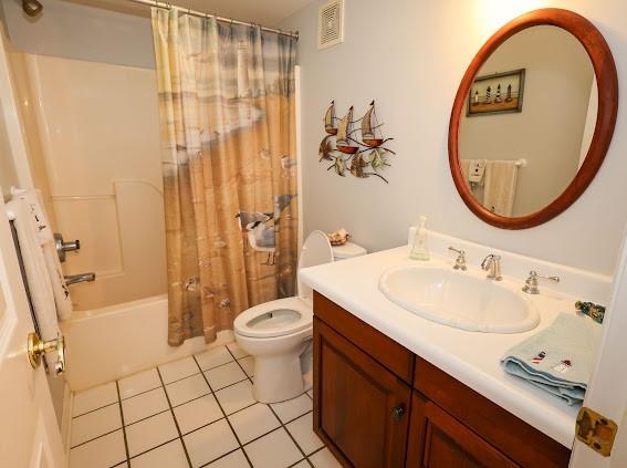 full bath featuring tile patterned flooring, vanity, toilet, and shower / tub combo with curtain