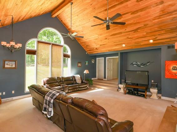 living room with wood ceiling, carpet, baseboards, a ceiling fan, and high vaulted ceiling