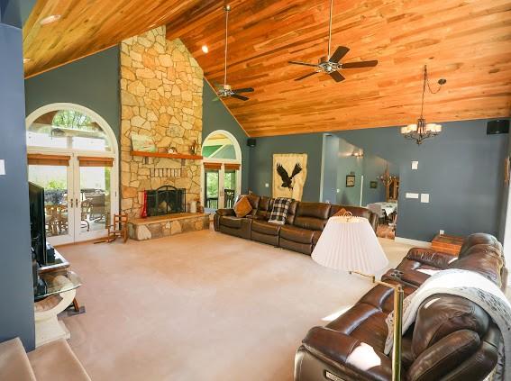 living area featuring carpet, a ceiling fan, wooden ceiling, high vaulted ceiling, and a fireplace
