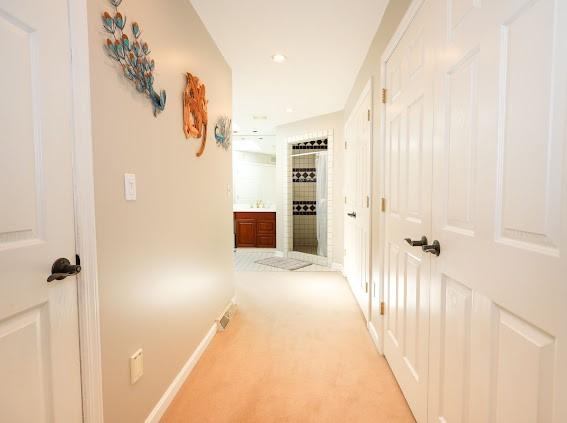 corridor featuring baseboards, light carpet, and recessed lighting