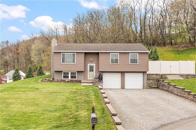split foyer home with a chimney, fence, driveway, a front yard, and a garage