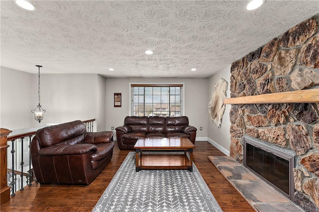 living room featuring a textured ceiling, baseboards, recessed lighting, wood finished floors, and a fireplace