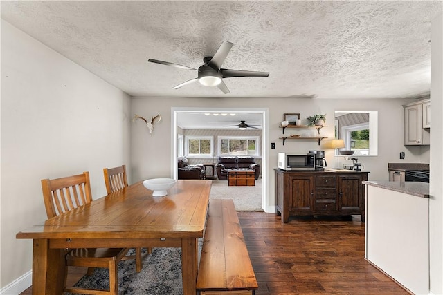 dining room featuring baseboards, a textured ceiling, a ceiling fan, and dark wood-style floors