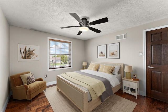 bedroom featuring dark wood-style floors, baseboards, a textured ceiling, and visible vents