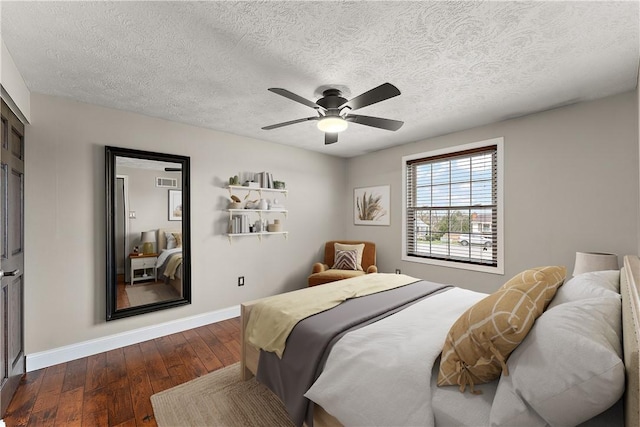 bedroom with dark wood finished floors, a textured ceiling, baseboards, and ceiling fan