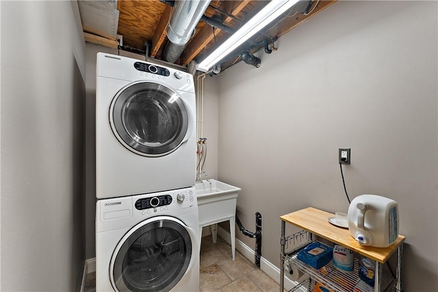 laundry area with baseboards, stacked washer / dryer, and laundry area