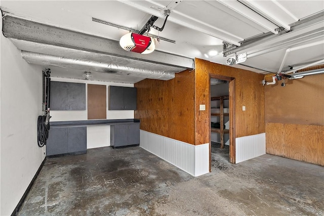 garage with wooden walls, baseboards, and a garage door opener