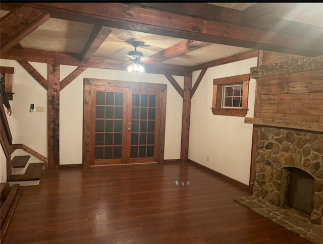unfurnished living room featuring ceiling fan, baseboards, wood finished floors, beamed ceiling, and a fireplace