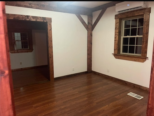 unfurnished room featuring a wall mounted air conditioner, dark wood finished floors, and baseboards