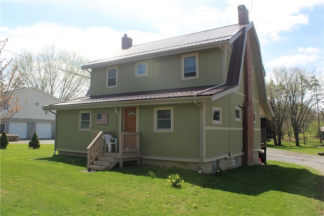 view of front facade featuring a chimney, a front yard, metal roof, and a garage