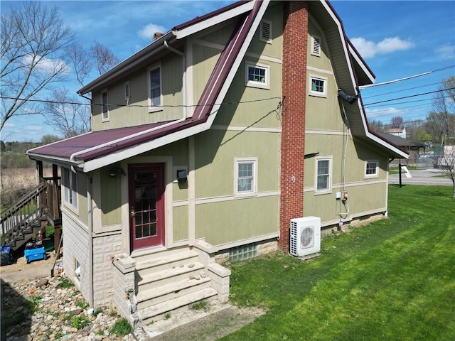back of property with entry steps, a cooling unit, and a lawn
