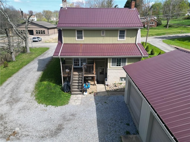 back of house featuring a chimney, a porch, metal roof, and stairs