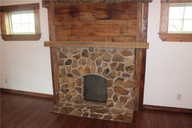detailed view of baseboards, wood finished floors, and a fireplace