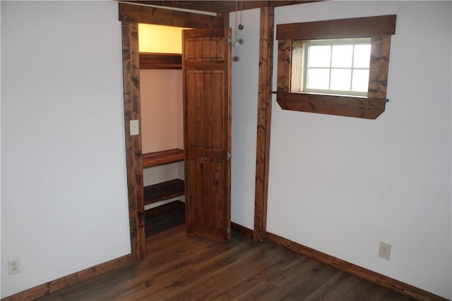 unfurnished bedroom featuring baseboards, wood finished floors, and a closet
