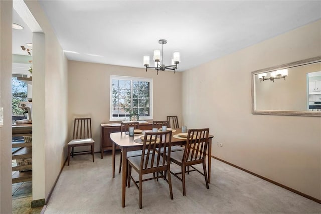 dining room featuring light colored carpet, baseboards, and a notable chandelier