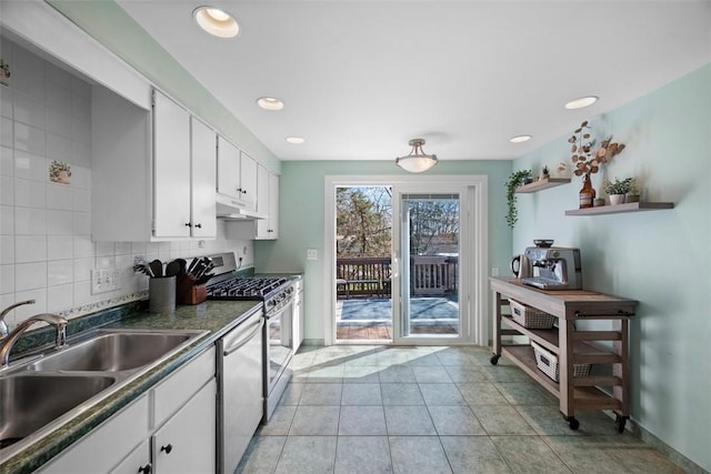 kitchen with under cabinet range hood, dark countertops, dishwashing machine, a sink, and stainless steel gas range