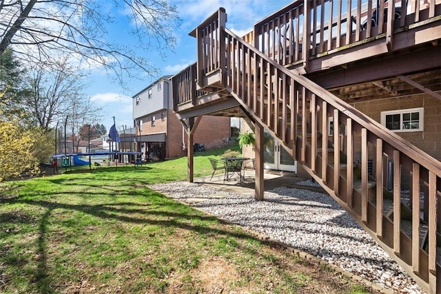 exterior space featuring stairway, a trampoline, a patio area, a lawn, and a deck