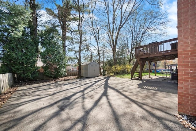 view of yard featuring fence, a shed, an outdoor structure, a patio, and a deck