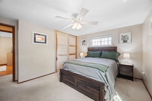 bedroom featuring light carpet, a ceiling fan, baseboards, and a closet