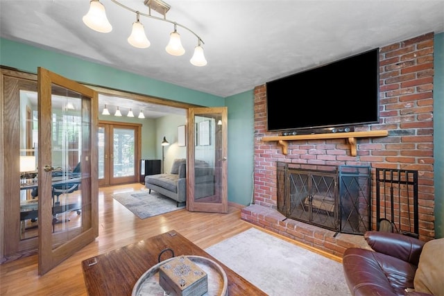 living area with french doors, wood finished floors, and a fireplace