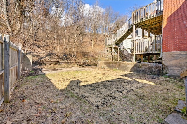 view of yard with fence, a wooden deck, and stairway