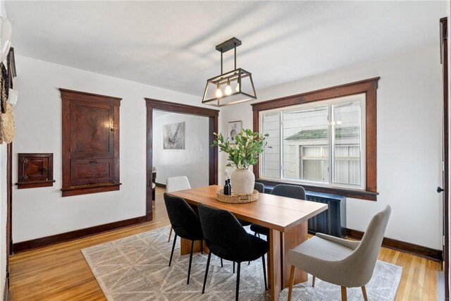 dining area featuring radiator, baseboards, a notable chandelier, and light wood-style flooring