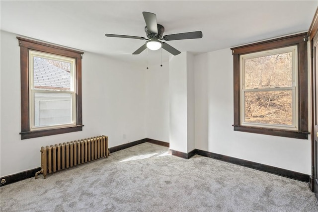carpeted empty room featuring ceiling fan, baseboards, and radiator heating unit