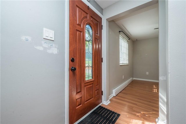 foyer with baseboard heating, baseboards, and light wood-style floors