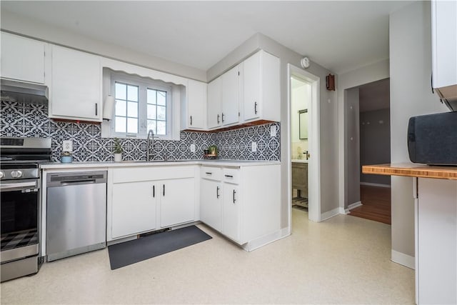 kitchen featuring decorative backsplash, a sink, appliances with stainless steel finishes, light countertops, and wall chimney exhaust hood