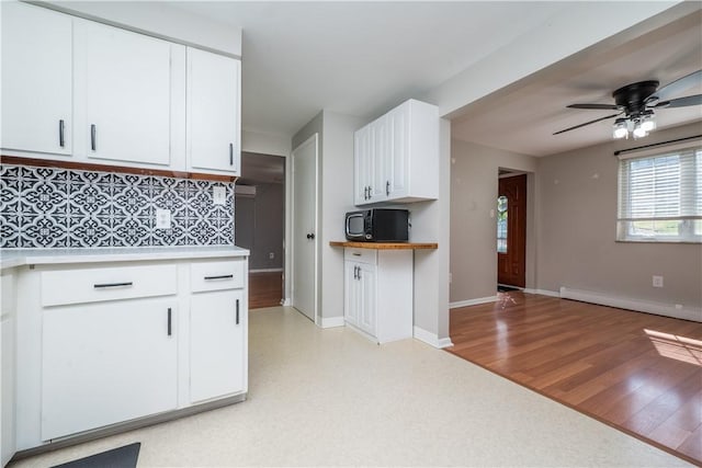 kitchen featuring tasteful backsplash, white cabinets, black microwave, ceiling fan, and light countertops