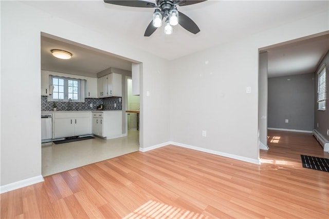 unfurnished living room with ceiling fan, light wood-type flooring, and baseboards