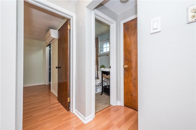 hall with light wood-type flooring and baseboards