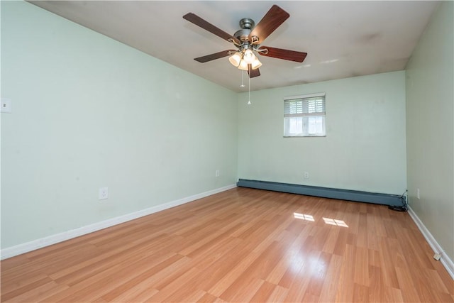 spare room with baseboards, ceiling fan, light wood finished floors, and a baseboard radiator