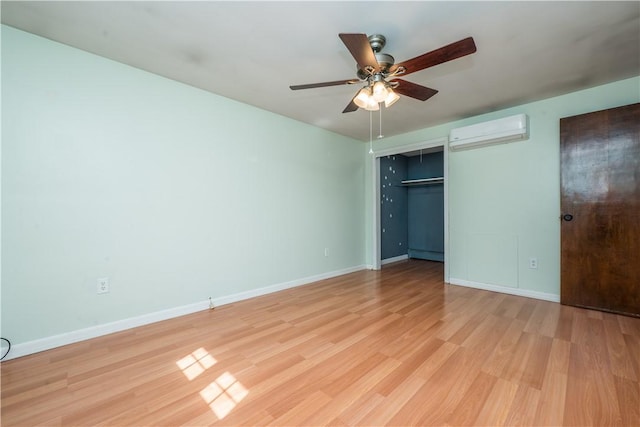 unfurnished bedroom featuring a wall mounted air conditioner, a closet, baseboards, and light wood-style floors