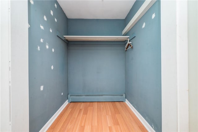 spacious closet featuring wood finished floors and a baseboard heating unit