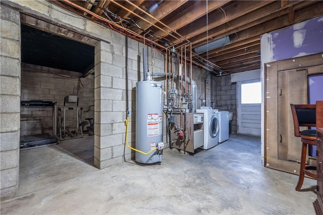 basement with gas water heater, washing machine and clothes dryer, concrete block wall, and a heating unit