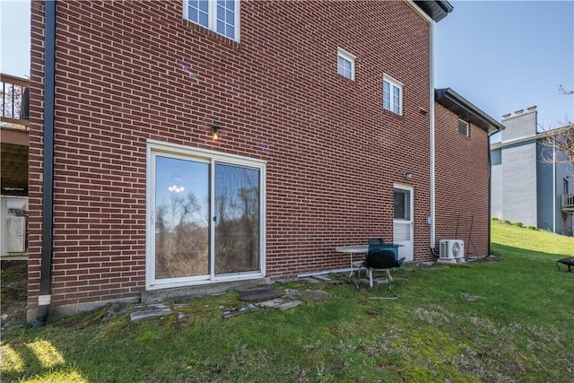 view of side of home featuring ac unit, a yard, and brick siding