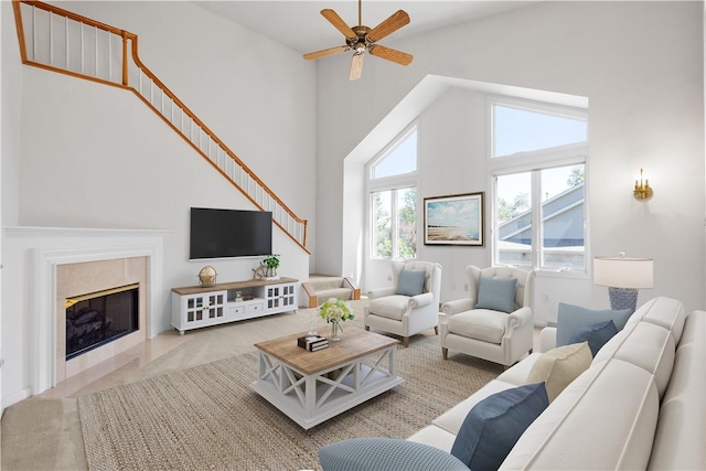 living room with high vaulted ceiling, a tile fireplace, stairs, and ceiling fan