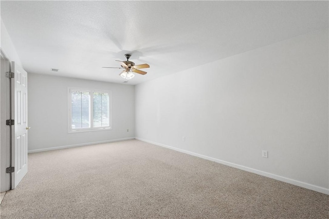 interior space with light colored carpet, baseboards, a ceiling fan, and visible vents