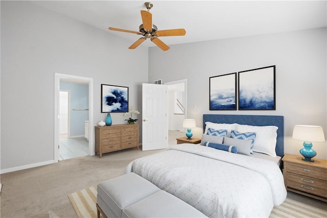 bedroom featuring baseboards, light colored carpet, ceiling fan, high vaulted ceiling, and connected bathroom