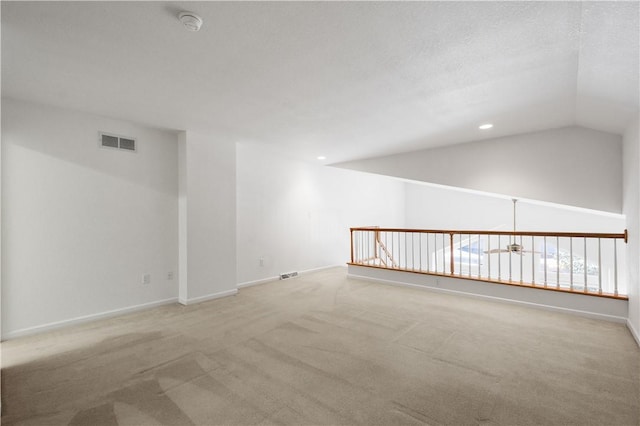 carpeted spare room featuring visible vents, vaulted ceiling, baseboards, and recessed lighting