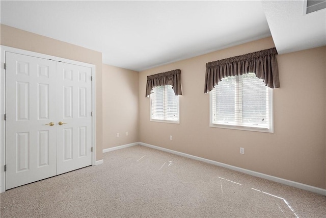 unfurnished bedroom featuring carpet, a closet, baseboards, and visible vents
