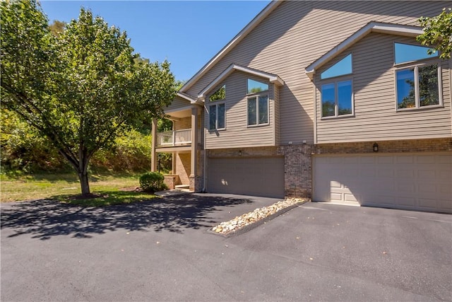 view of front facade featuring aphalt driveway, brick siding, and a garage